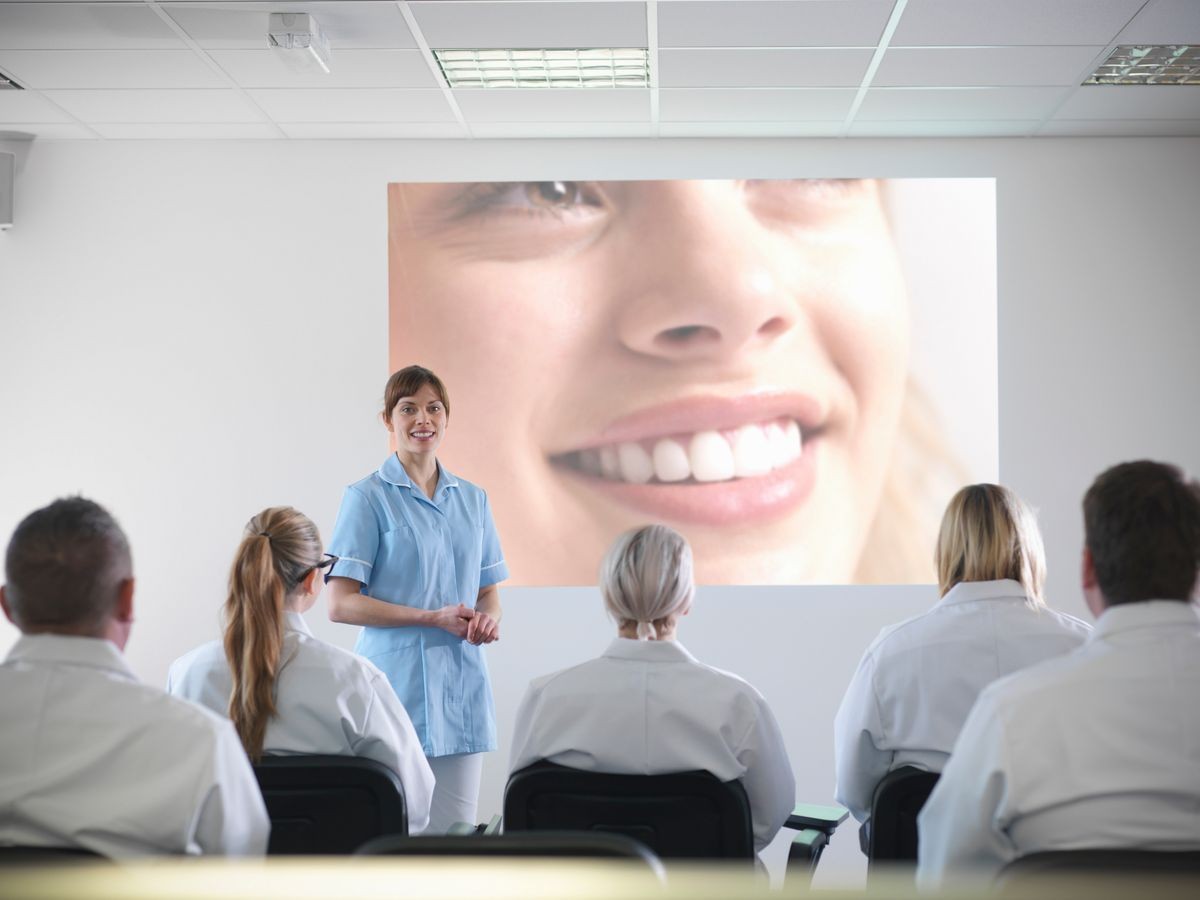 Apprentice dentists learning from professional using screens in dentist college